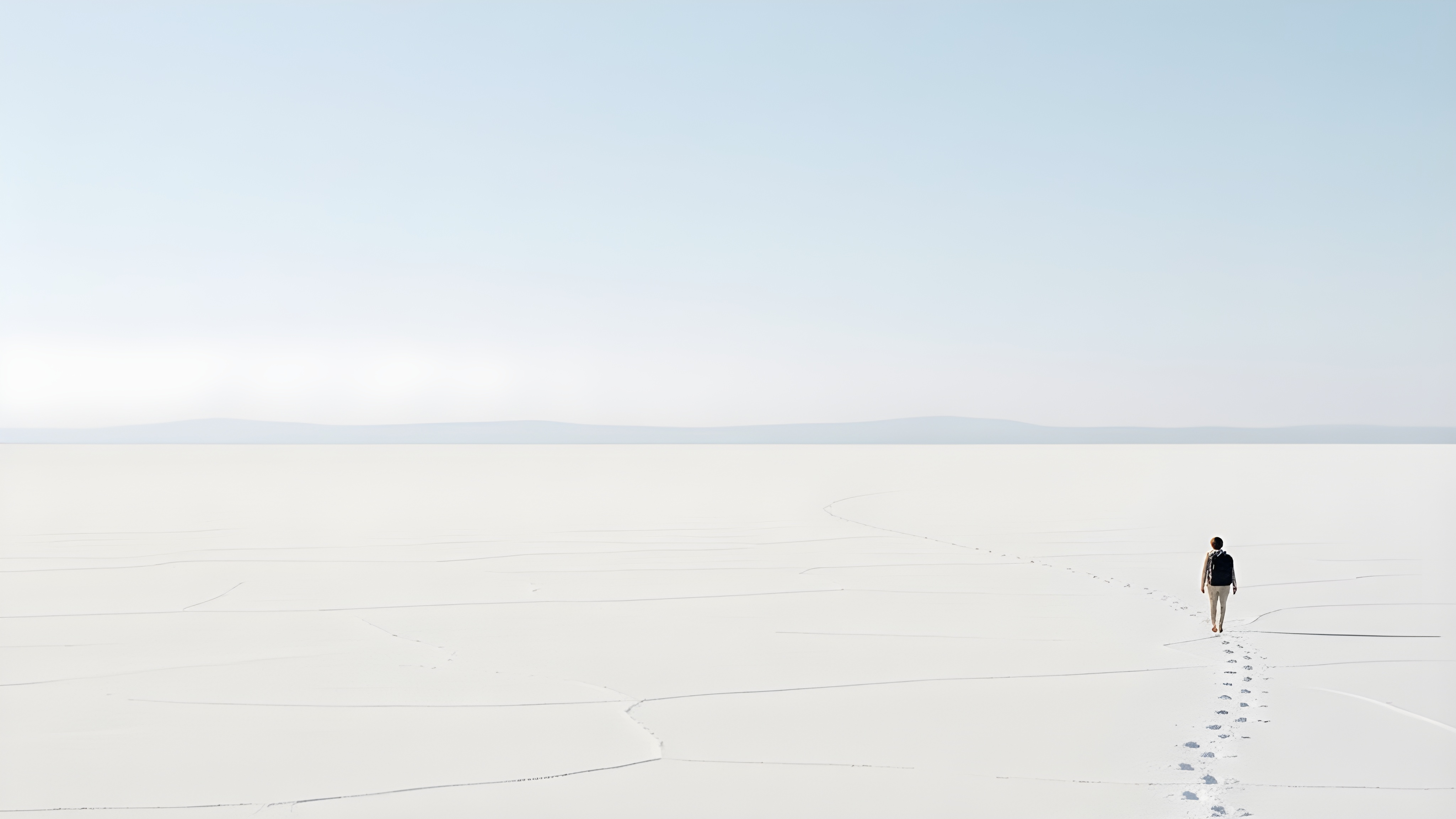 Person walking into the distance on white salt flats, leaving footprints